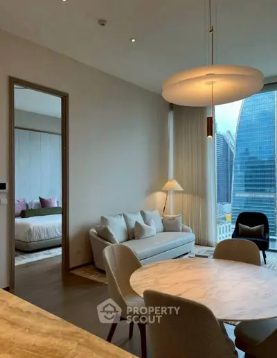 Modern living room with city view, elegant furniture, and open layout leading to a cozy bedroom.
