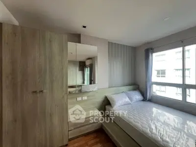 Cozy bedroom with natural light, featuring a comfortable bed and modern wooden wardrobe.
