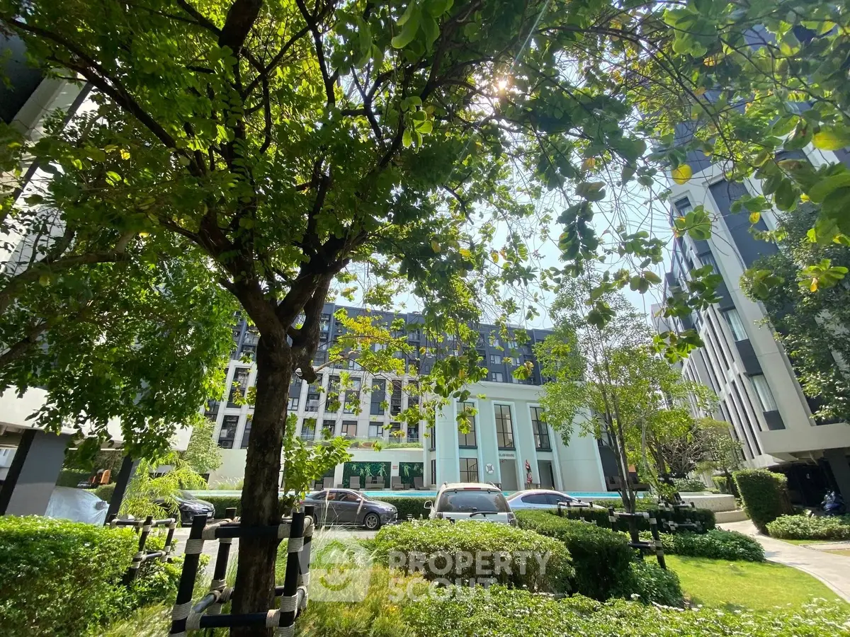 Modern residential building with lush green garden and parked cars