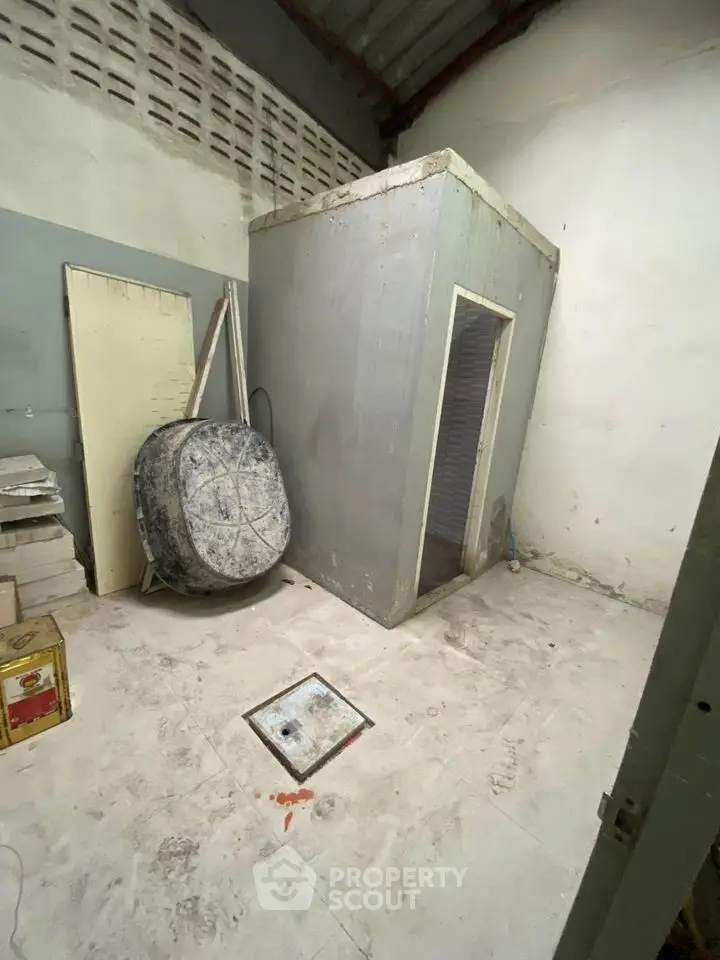 Spacious storage room with high ceiling and concrete flooring, ideal for versatile use.