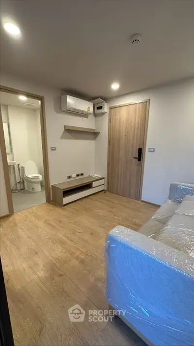 Spacious bedroom with en-suite bathroom, modern air conditioning, and elegant wood flooring, perfect for comfortable living.