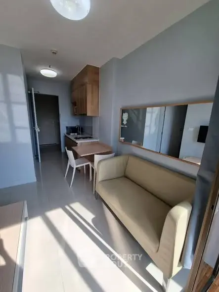 Modern apartment interior with cozy living area and compact kitchen, featuring sleek furniture and natural light.