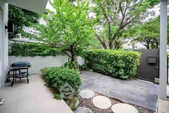 Charming garden with lush greenery and patio area in a serene residential setting.