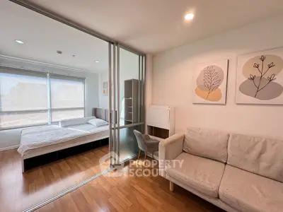 Modern studio apartment with cozy living area and bedroom separated by glass partition, featuring stylish decor.