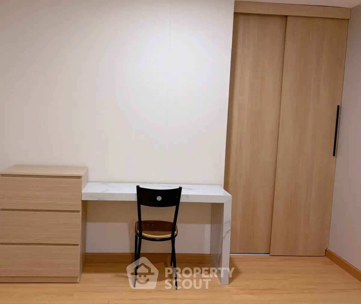 Minimalist study area with wooden desk, chair, and storage cabinet in modern apartment.