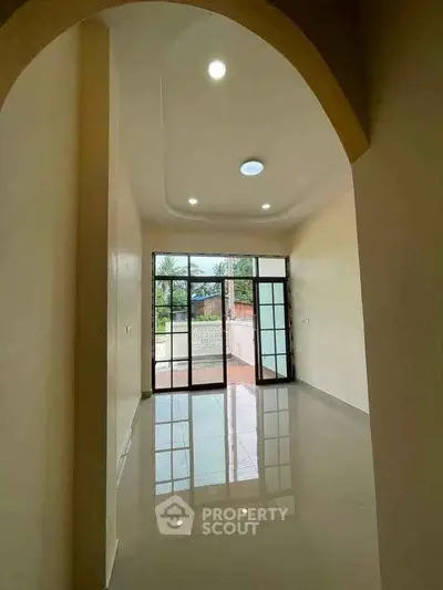 Spacious room with large windows and glossy floor, offering abundant natural light and outdoor view.