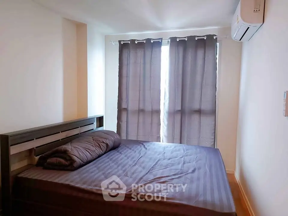 Cozy bedroom with modern air conditioning and natural light through large windows.
