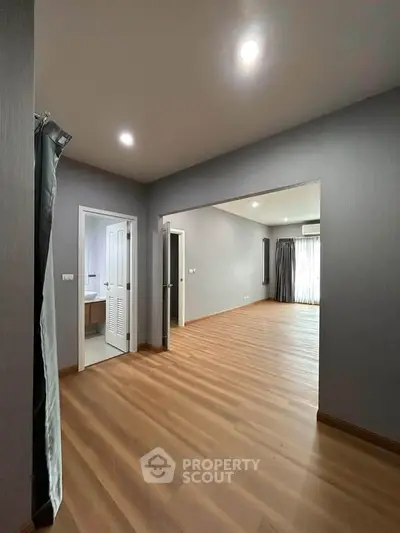 Spacious modern living room with wooden flooring and ample natural light.