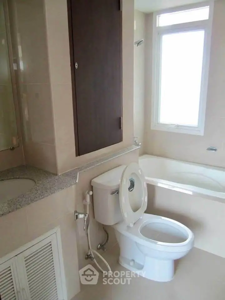 Modern bathroom with bathtub and large window offering natural light.