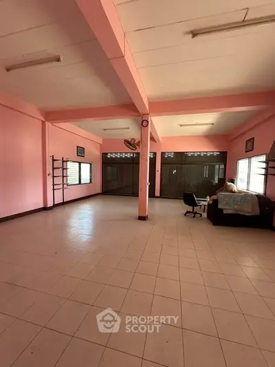 Spacious open-plan living area with pink walls and tiled flooring, ideal for customization.
