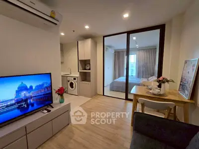 Modern apartment interior with open living room, kitchen, and bedroom view.