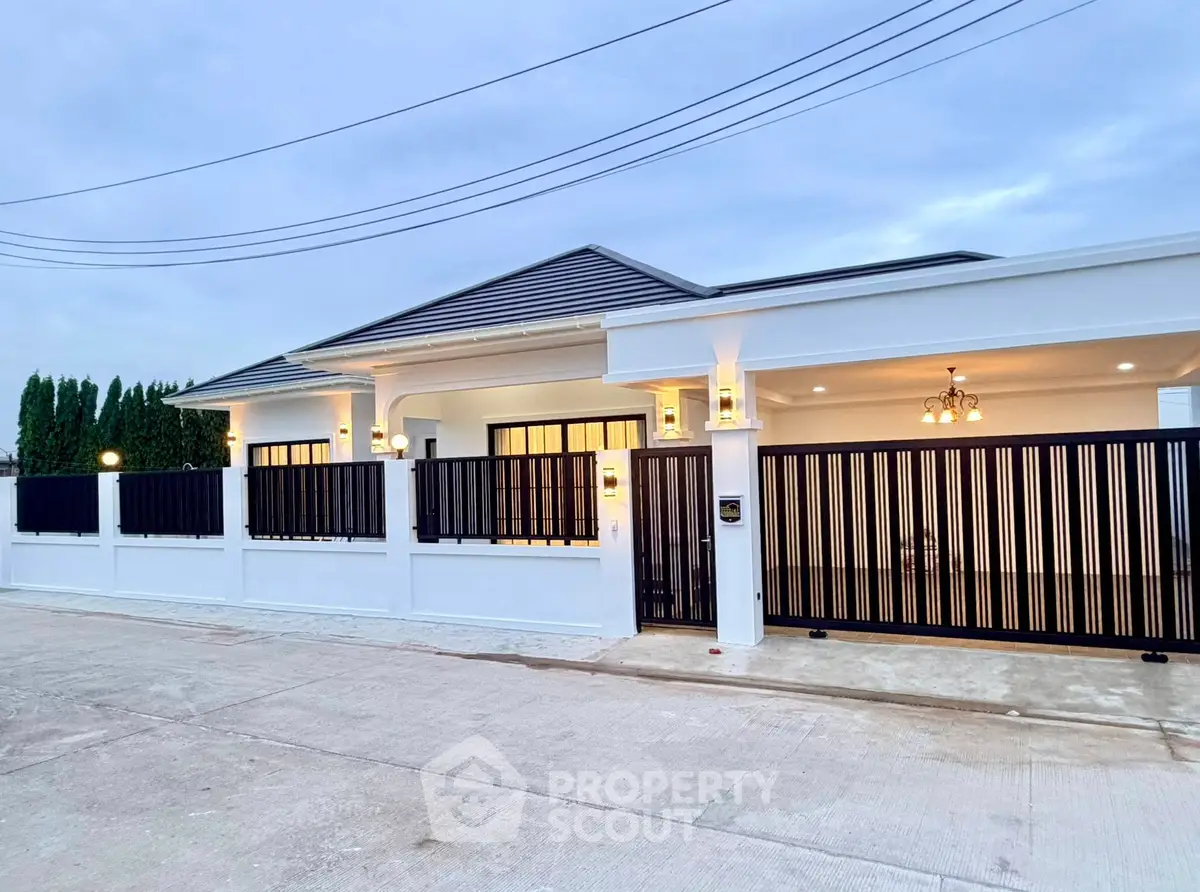 Modern single-story house with elegant fence and warm exterior lighting.