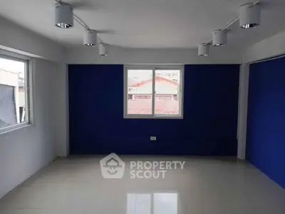 Spacious room with modern lighting and large windows, ideal for versatile use in a vibrant property.