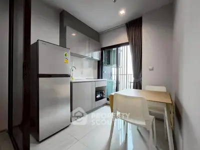 Modern kitchen with sleek cabinetry, dining area, and balcony view in a stylish apartment.