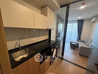 Modern apartment kitchen with sleek design and open layout leading to cozy living room.