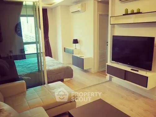 Modern apartment interior with cozy living room and stylish bedroom separated by glass partition.