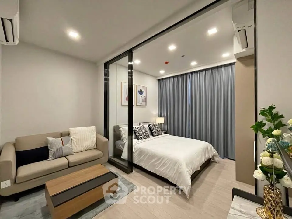 Modern bedroom with glass partition and cozy living area in stylish apartment.