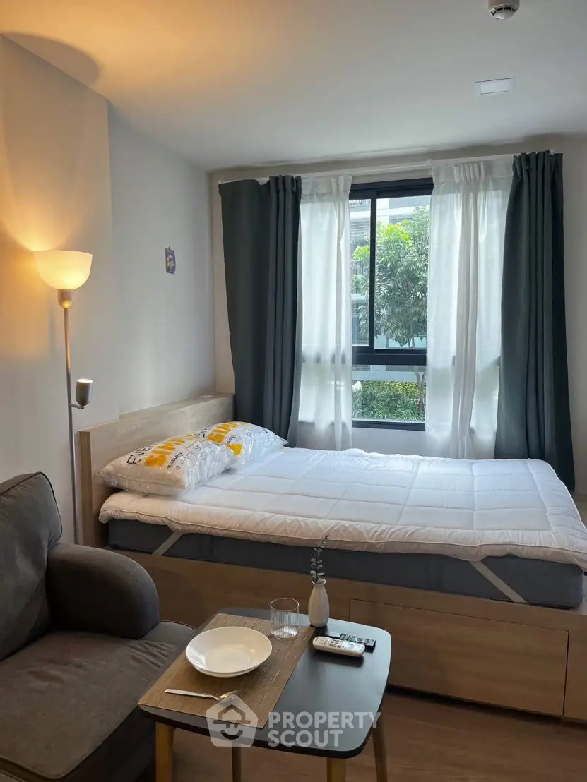 Cozy bedroom with natural light, modern decor, and comfortable furnishings.