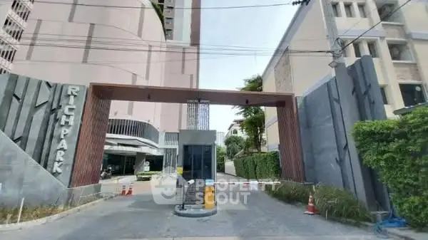 Modern apartment building entrance with secure gated access and lush greenery.