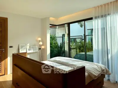Bright and modern bedroom with large windows and garden view, featuring elegant wooden furniture.