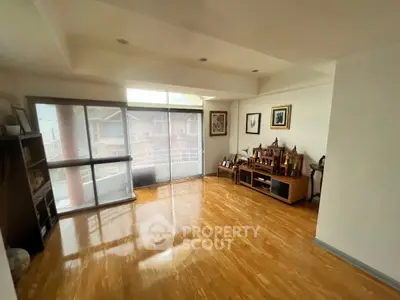 Spacious living room with wooden flooring and large windows for natural light.