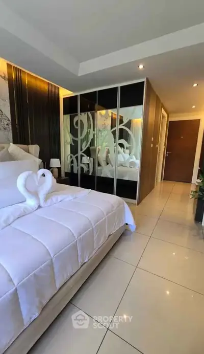 Luxurious bedroom with elegant decor and mirrored wardrobe in modern apartment.