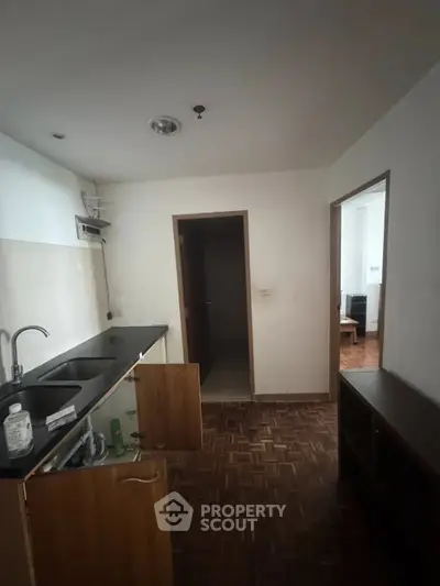 Spacious kitchen with parquet flooring and modern fixtures in a cozy apartment.