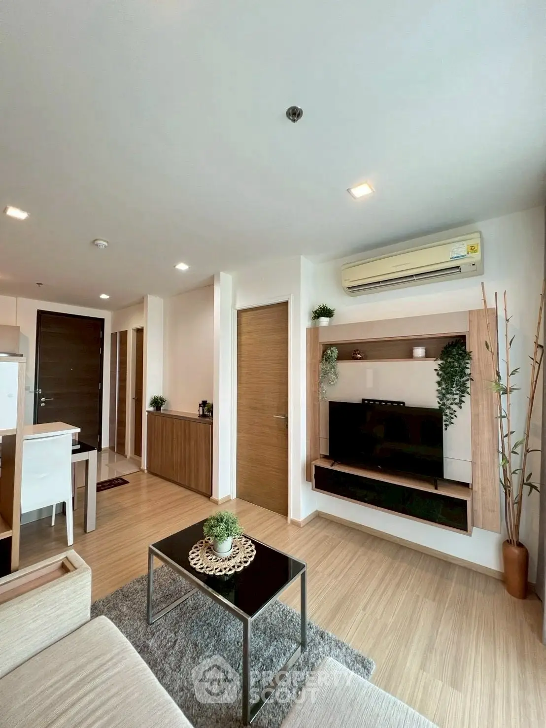 Modern living room with sleek furniture and built-in TV unit, featuring wooden flooring and stylish decor.