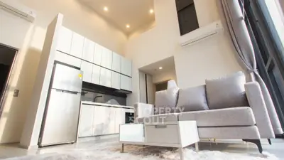 Modern high-ceiling living room with sleek kitchen and cozy gray sofa