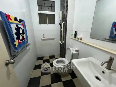 Modern bathroom with checkered floor tiles and sleek fixtures in a contemporary home.