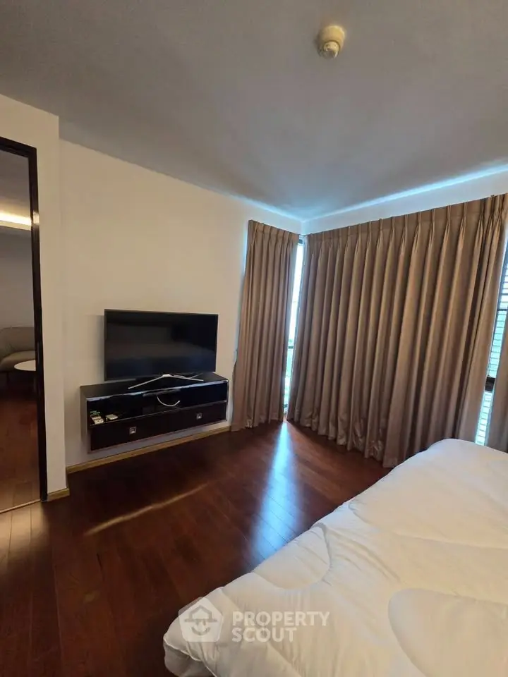 Spacious bedroom with wooden flooring and large windows for natural light
