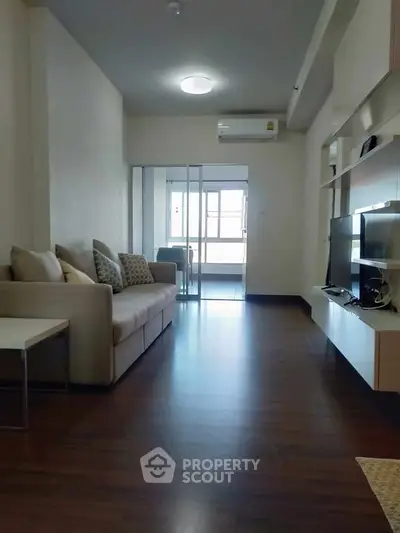 Modern living room with sleek design and natural light, featuring a comfortable sofa and entertainment unit.