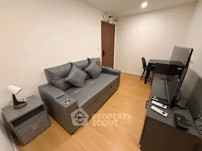 Modern living room with sleek gray sofa, flat-screen TV, and wooden flooring in a cozy apartment.