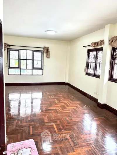 Spacious living room with polished wooden floors and large windows, perfect for natural light.