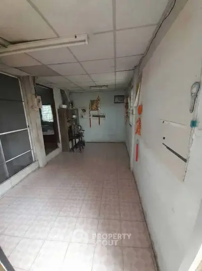 Spacious hallway with tiled flooring and simple decor, ideal for renovation opportunities.
