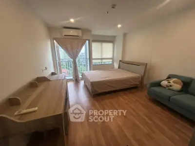 Spacious bedroom with wooden flooring, large window, and cozy seating area.