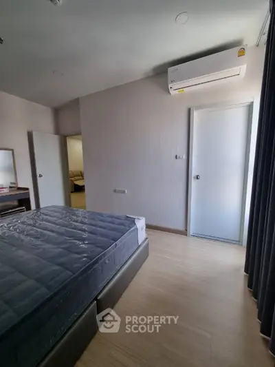 Spacious bedroom with large windows, modern air conditioning unit, and elegant wood flooring, ready for personalization in a prime location.