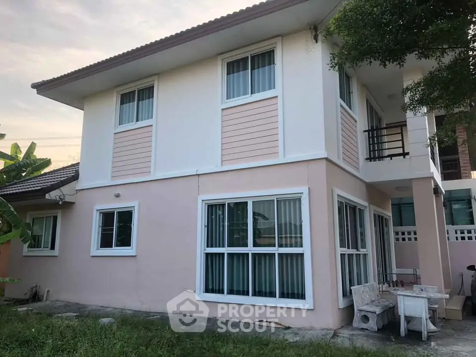 Charming two-story house with large windows and a cozy outdoor seating area, perfect for family living.