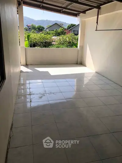 Spacious tiled balcony with scenic view of greenery and distant mountains, perfect for relaxation.