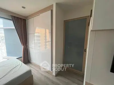 Modern bedroom with large window and built-in wardrobe in a high-rise apartment.