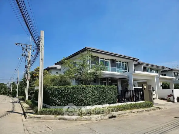 Modern two-story house with lush greenery and clear blue sky