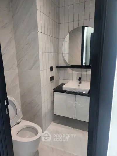 Modern bathroom with sleek design, featuring a round mirror and contemporary fixtures.