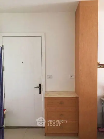 Modern apartment entrance with sleek wooden storage unit and white door