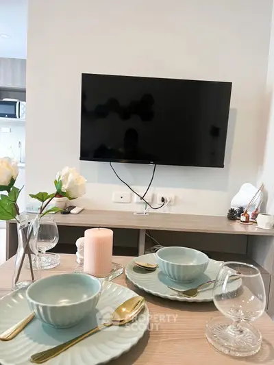 Modern dining area with elegant table setting and wall-mounted TV in a stylish apartment.