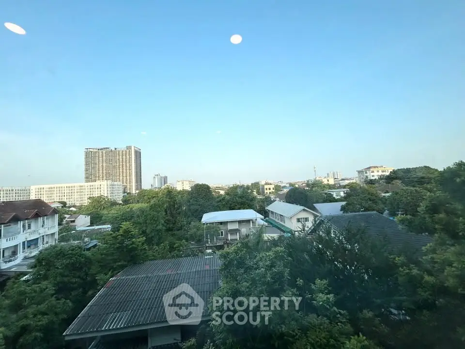 Stunning cityscape view from a high-rise building showcasing lush greenery and urban skyline.
