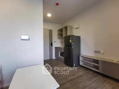 Modern compact kitchen with sleek appliances and wooden flooring in a cozy apartment.