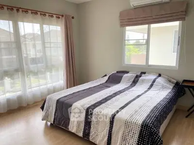 Spacious bedroom with large windows and modern decor in a bright home.