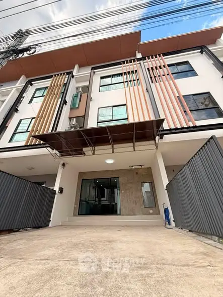 Modern multi-story building with unique facade design and gated entrance, ideal for urban living.