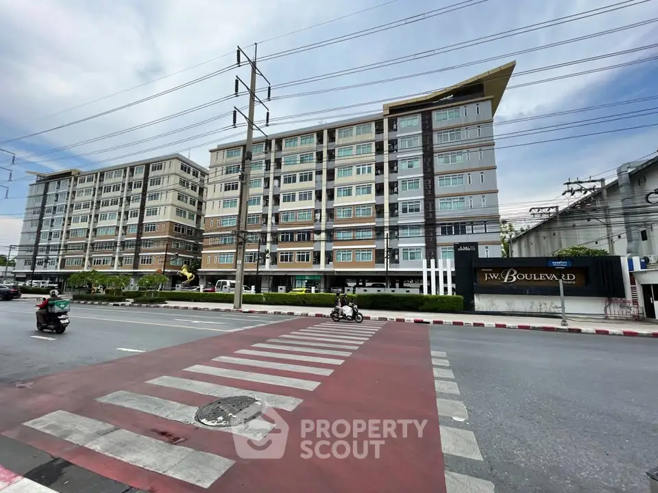 Modern multi-story residential building with street view and crosswalk in urban setting.