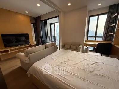 Modern studio apartment with cozy living area and city view, featuring a comfortable bed and stylish decor.